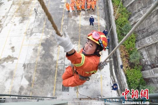 图为消防指战员利用绳索攀爬高层。　娄渊焘 摄